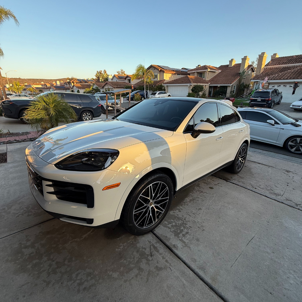 White Porsche SUV with pristine ceramic coating finish in residential driveway showing professional detailing results