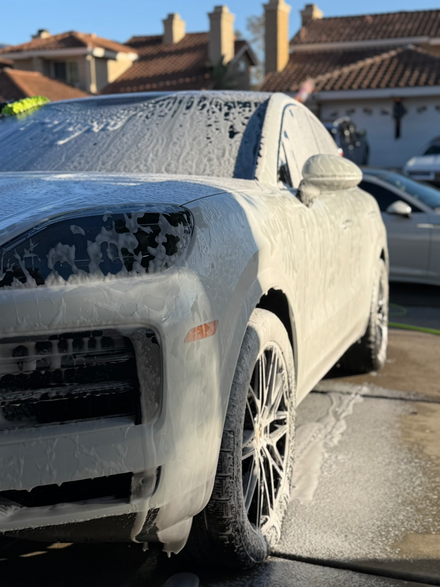 Mobile detailing service showing white luxury SUV covered in premium foam pre-treatment
